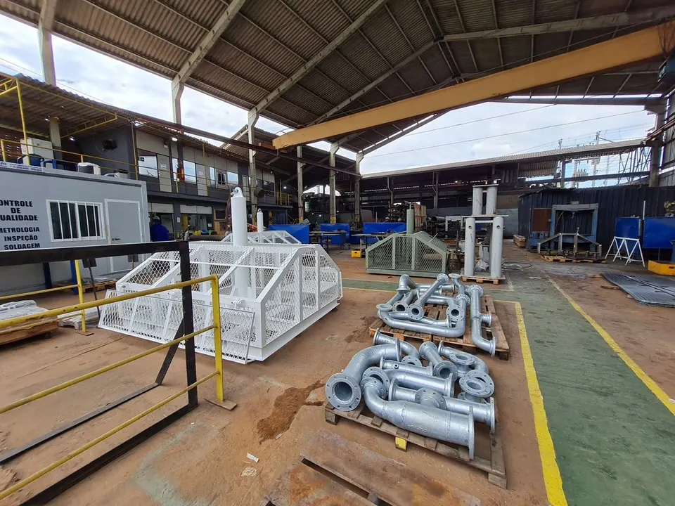 White painted mesh protection structure and flanged piping spools in the factory yard